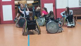 Frauen und Männer spielen Rugby im Rollstuhl