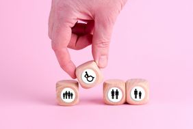 Eine Hand stellt einen W&uuml;rfel mit einem Rolli drauf zwischen andere W&uuml;rfel, die Menschen zeigen.