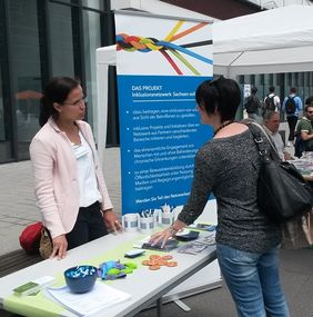 Blick auf den Stand - Mitarbeiter im Gespräch mit Besuchern