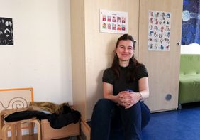 lächelnde Frau mit langen Haaren sitzend vor einem Schrank