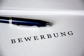 Ein blauer Kugelschreiber liegt auf einem Blatt Papier auf dem "Bewerbung" steht