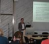  Referentin spricht am Pult und schaut zu den Teilnehmern