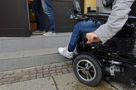 Rollstuhlfahrer steht vor Treppenstufe und T&uuml;r - kommt nicht hinein