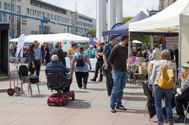 Teilnehmer*innen schlendern und fahren &uuml;ber den Markt der Inklusion mit vielen St&auml;nden