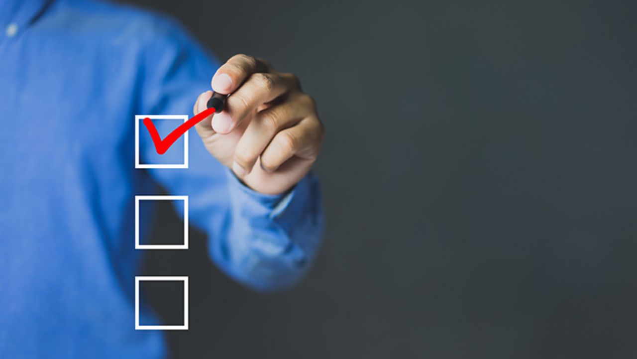 Eine Männerhand hakt das erste Kästchen einer Checkliste ab