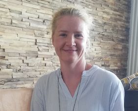 Freundlich l&auml;chelnde Frau mit blonden, zusammengebundenen Haaren, blickt in Kamera