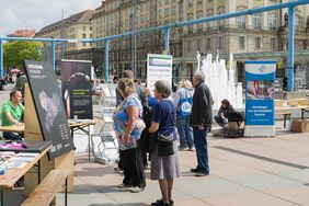 Besucher*innen stehen vor St&auml;nden mit Roll-Ups und gucken sich die Angebote an