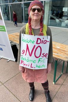 Eine Frau lacht in die Kamera. Sie ist als Pippi Langstrumpf verkleidet und hat ein Schild umh&auml;ngen, auf dem steht: Welche Diagnose bek&auml;me Frl. Pippi L. heute?