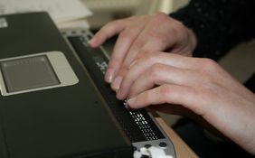 Braille-Leiste am Laptop angeschlossen - Blick auf schreibende H&auml;nde