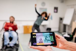 Eine Person im Rollstuhl und eine weitere Person, die vor der Kamera des MotionComposers tanzen