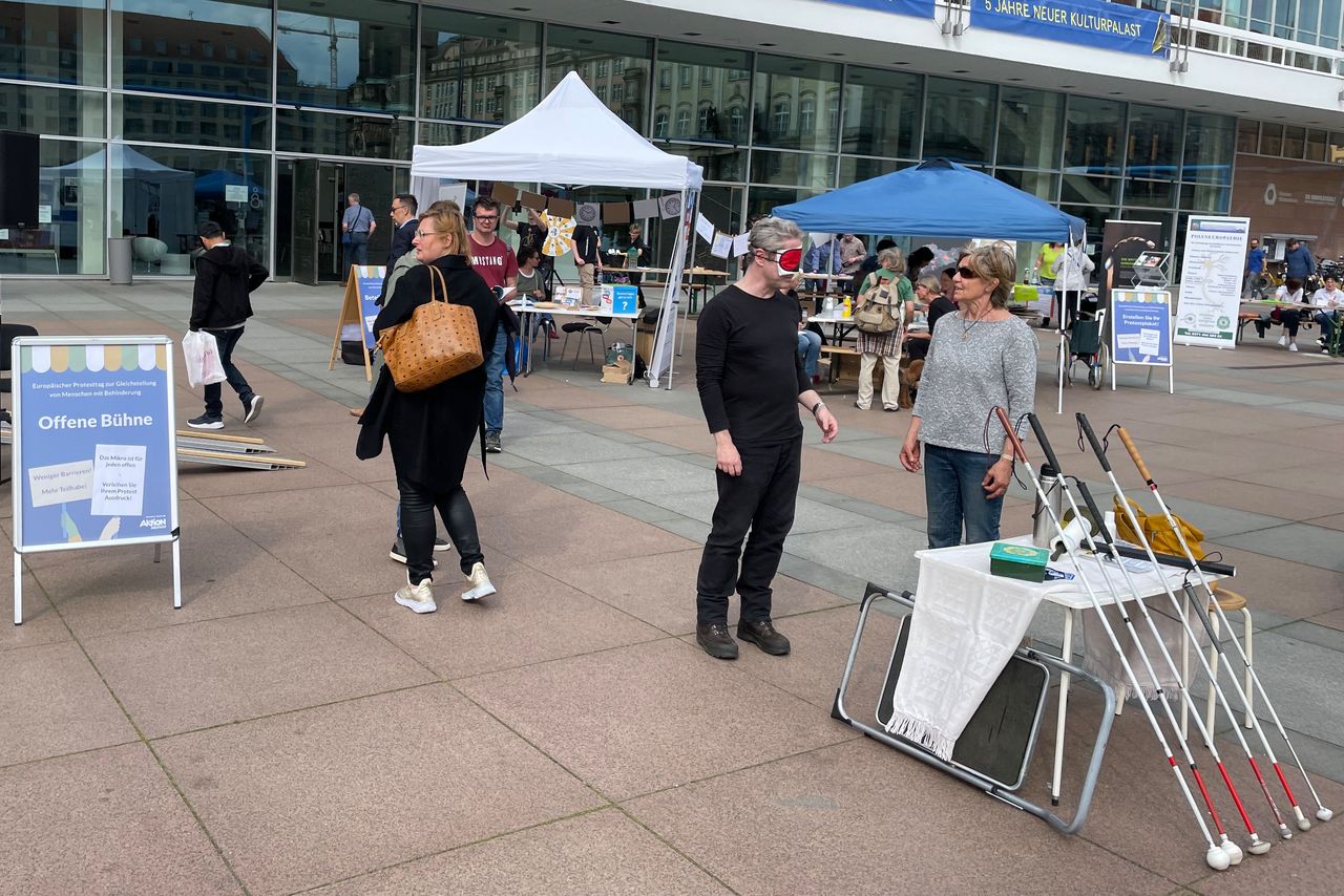 Ein Mann trägt eine Augenmaske und probiert den Blinden-Parcours mit Langstock aus
