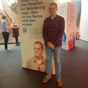 Andr&eacute; Brendle vor der Ausstellungswand mit seinem Portr&auml;t