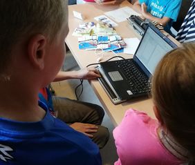 Kinder blicken auf Rechner mit Brailleleiste